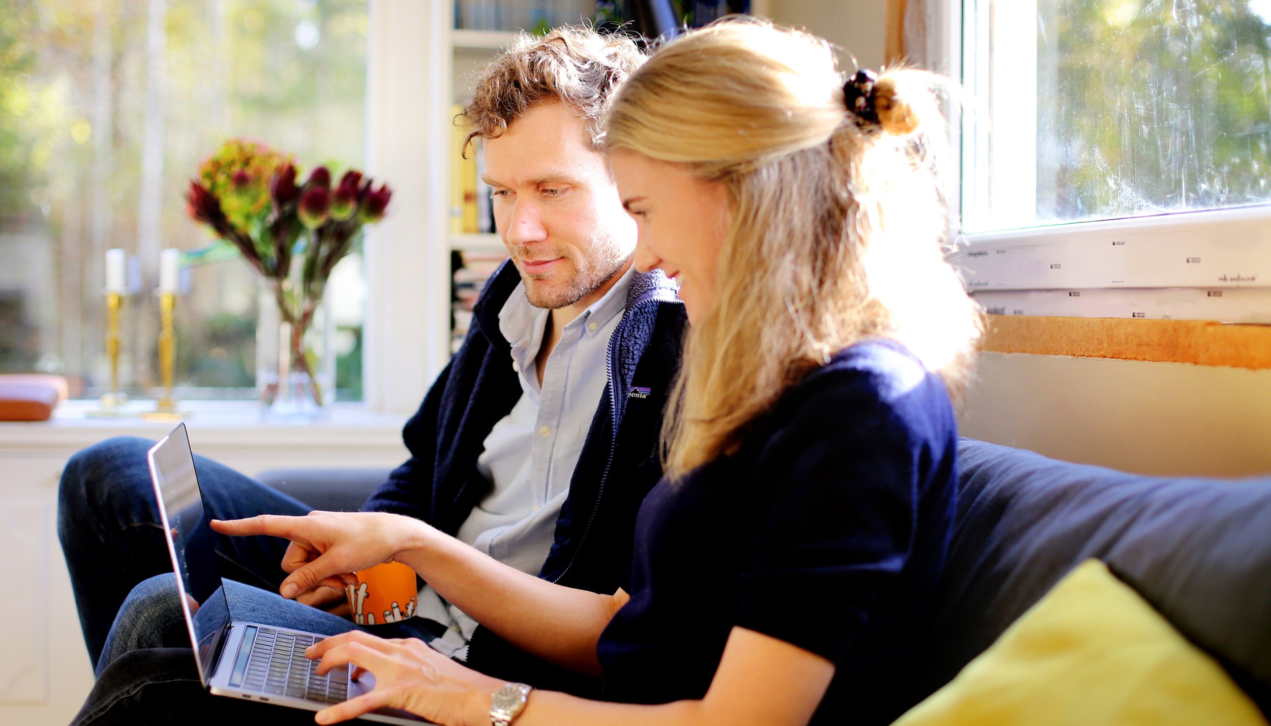 Par i sofa ser og peker på dataskjerm